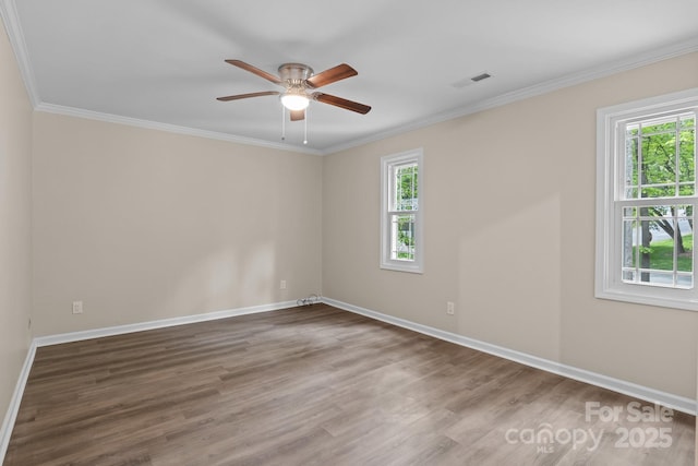 unfurnished room with baseboards, wood finished floors, visible vents, and crown molding
