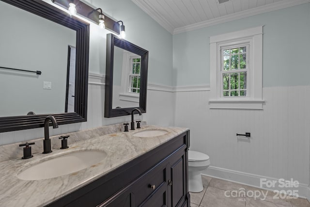 full bath featuring tile patterned floors, toilet, wainscoting, and a sink