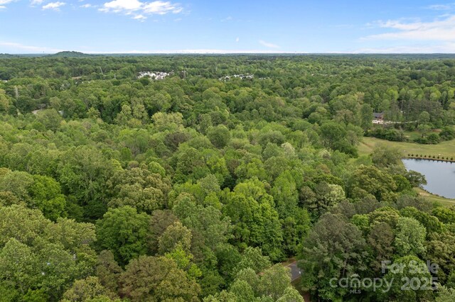 aerial view featuring a wooded view and a water view