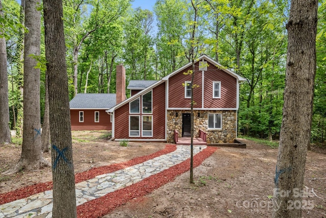 view of front of house with stone siding and a chimney