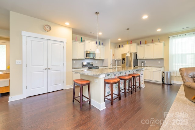 kitchen featuring appliances with stainless steel finishes, dark wood-type flooring, a sink, white cabinetry, and a breakfast bar