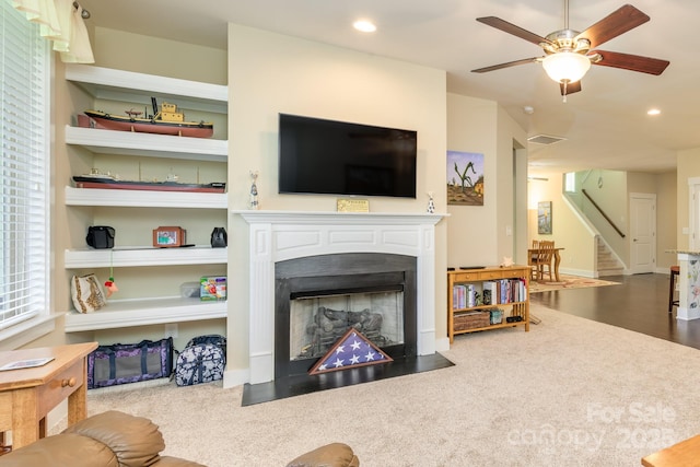 living area with stairway, a fireplace with flush hearth, ceiling fan, recessed lighting, and carpet
