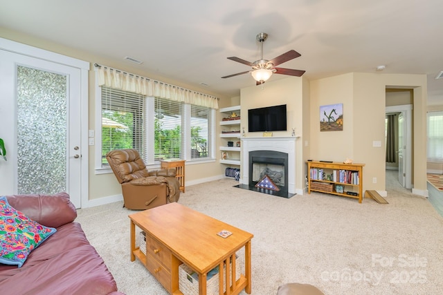 living room with carpet floors, a fireplace with flush hearth, ceiling fan, and baseboards