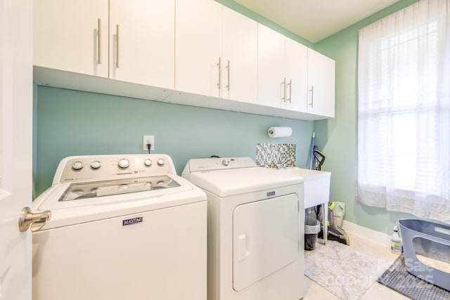 clothes washing area with cabinet space, washing machine and clothes dryer, and baseboards