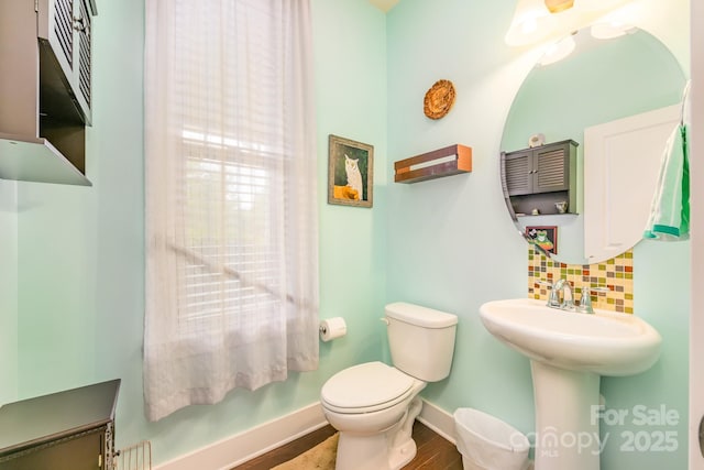 bathroom featuring backsplash, baseboards, toilet, and wood finished floors