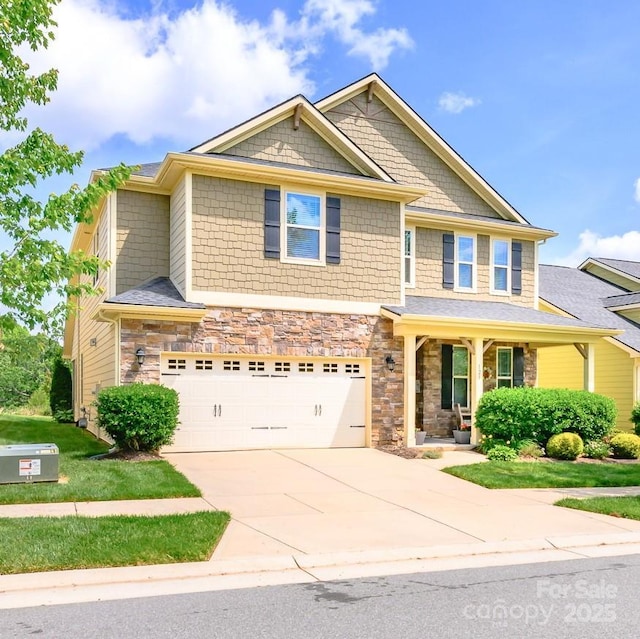 craftsman-style house with a garage, driveway, covered porch, and stone siding