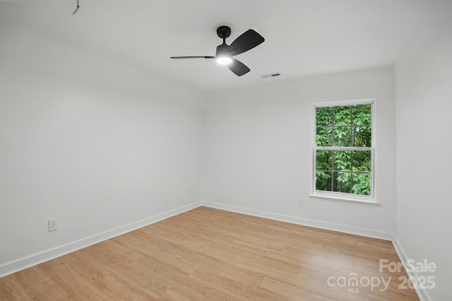 empty room featuring visible vents, ceiling fan, light wood-type flooring, and baseboards