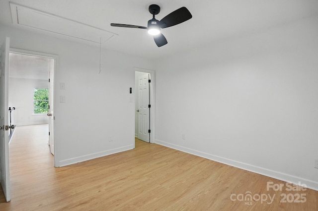 unfurnished room featuring baseboards, light wood-type flooring, attic access, and a ceiling fan