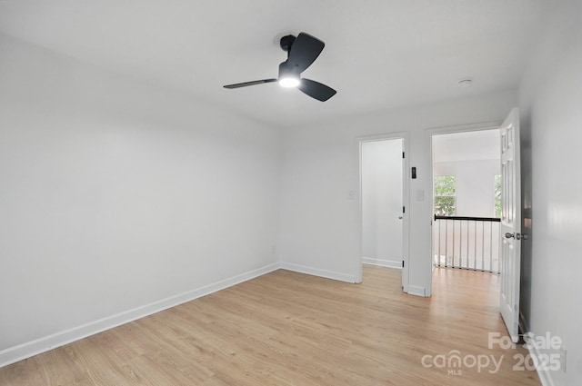 empty room featuring light wood-type flooring, a ceiling fan, and baseboards