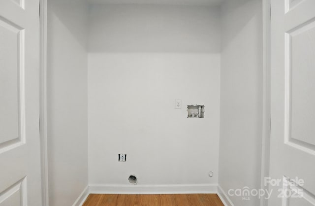 clothes washing area with electric dryer hookup, hookup for a washing machine, wood finished floors, and baseboards