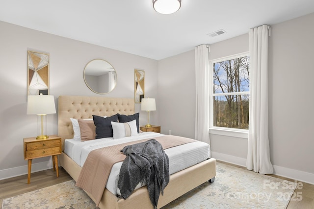 bedroom with wood finished floors, visible vents, and baseboards