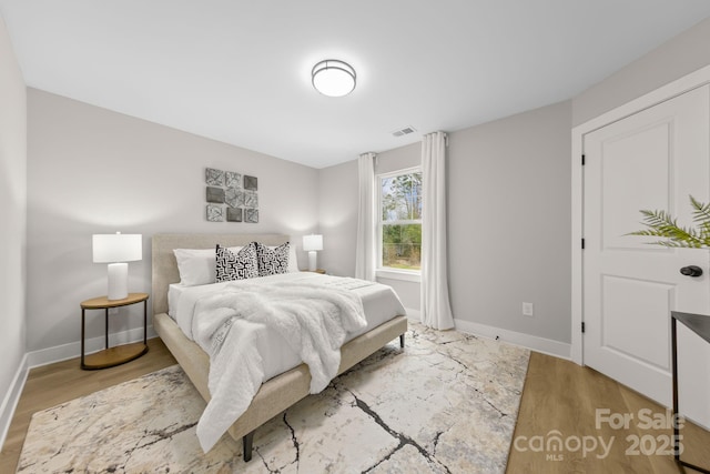 bedroom featuring baseboards, visible vents, and wood finished floors