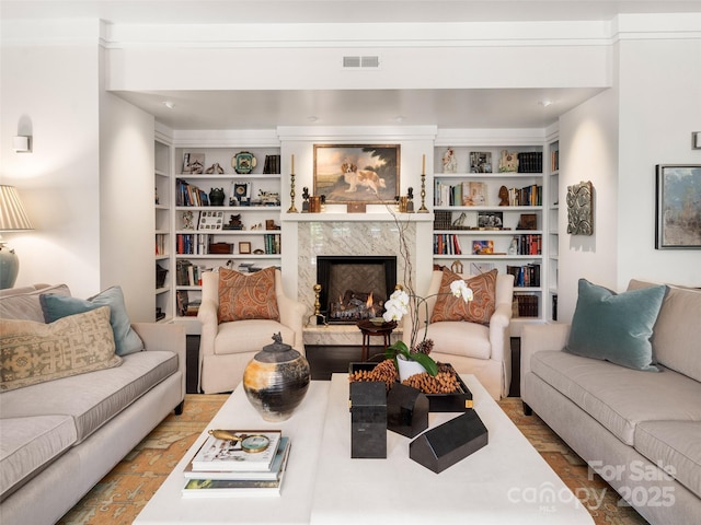 living room with visible vents, a fireplace, and built in features