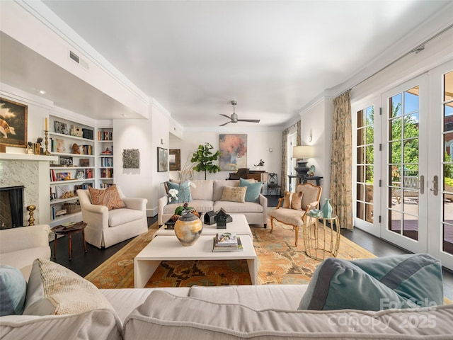 living area featuring visible vents, wood finished floors, ceiling fan, crown molding, and a high end fireplace