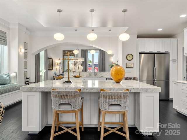 kitchen with freestanding refrigerator, arched walkways, dark wood-type flooring, and a sink