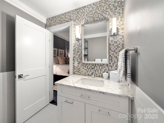 bathroom with tasteful backsplash, connected bathroom, vanity, tile walls, and tile patterned flooring