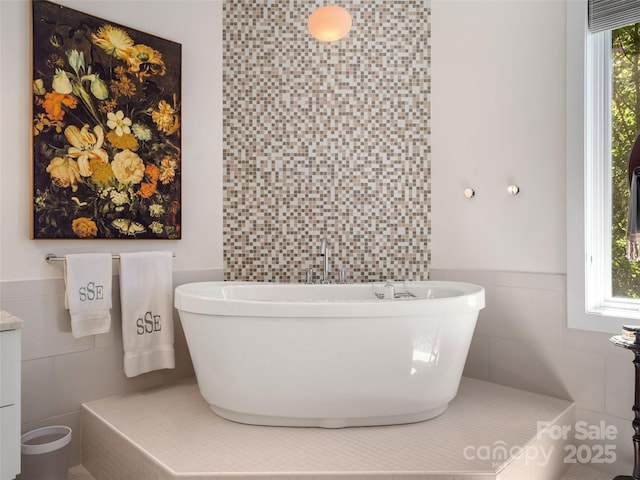 full bath with tile walls, wainscoting, and a freestanding tub