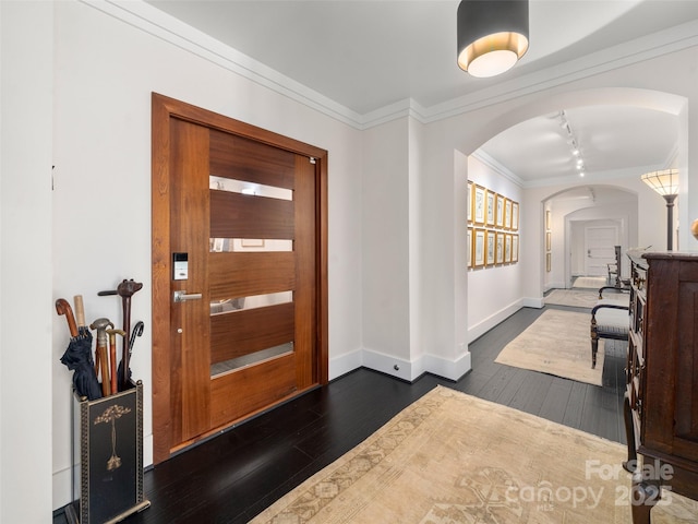 entrance foyer featuring baseboards, dark wood-style floors, arched walkways, and ornamental molding
