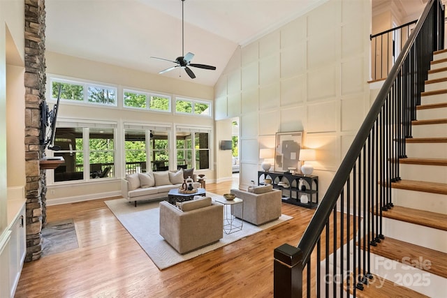 living room featuring stairs, wood finished floors, ceiling fan, and high vaulted ceiling