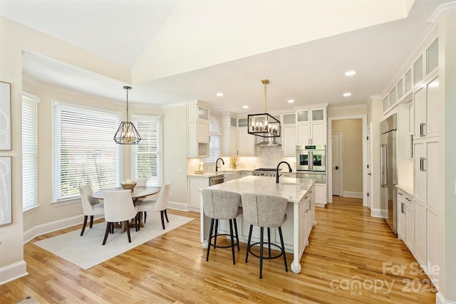 kitchen with a kitchen bar, stainless steel appliances, a wealth of natural light, and a notable chandelier