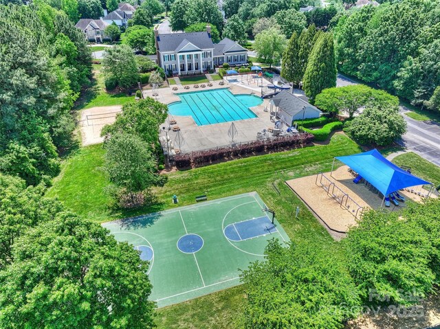 aerial view of property and surrounding area featuring a pool and a tree filled landscape