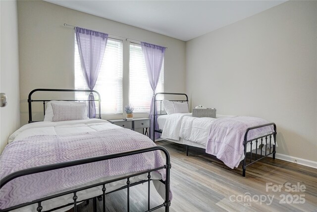 bedroom featuring baseboards, multiple windows, and wood finished floors