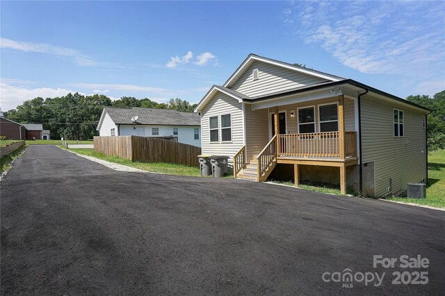 bungalow-style house featuring a porch, central AC, fence, and aphalt driveway