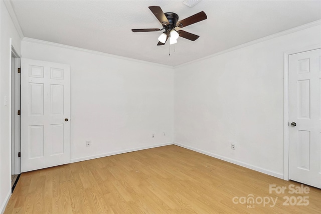 spare room featuring ornamental molding, light wood-style floors, a ceiling fan, and baseboards
