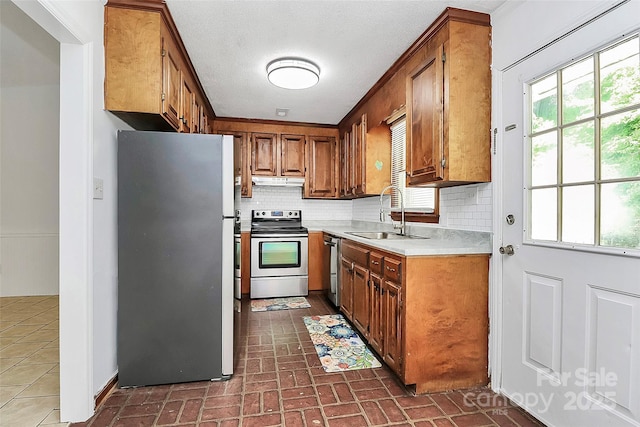 kitchen featuring a sink, brown cabinetry, light countertops, appliances with stainless steel finishes, and decorative backsplash