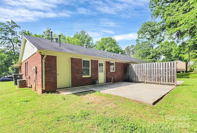rear view of house featuring a yard, a patio, brick siding, and central air condition unit