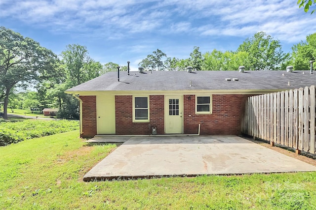 rear view of property with a patio area, brick siding, a lawn, and fence