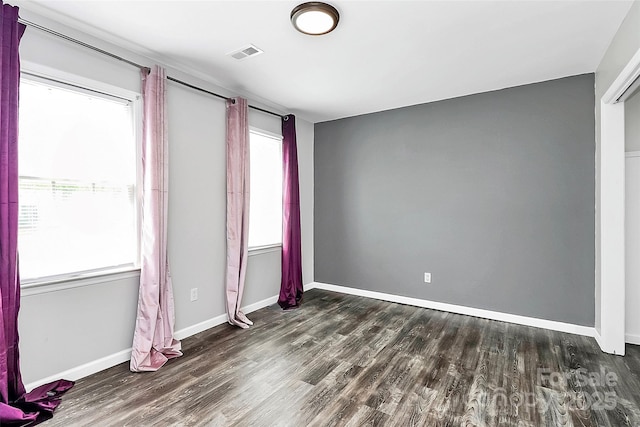 spare room featuring baseboards, visible vents, and wood finished floors