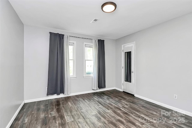 empty room featuring visible vents, wood finished floors, and baseboards