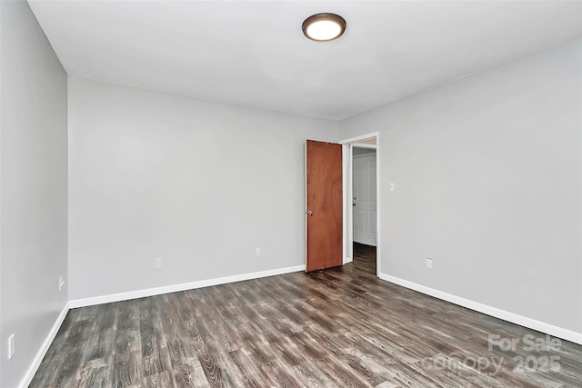 empty room featuring dark wood finished floors and baseboards
