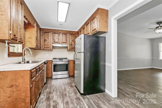 kitchen featuring stainless steel appliances, dark wood-style flooring, a sink, brown cabinets, and light countertops