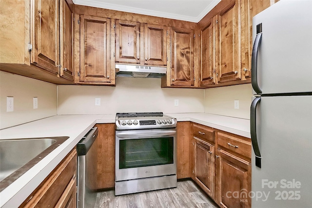 kitchen featuring under cabinet range hood, light countertops, appliances with stainless steel finishes, and brown cabinets