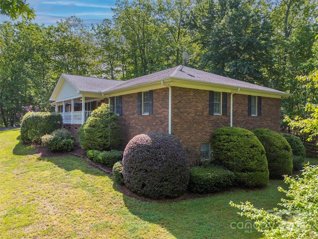 view of property exterior featuring brick siding, a yard, and a sunroom
