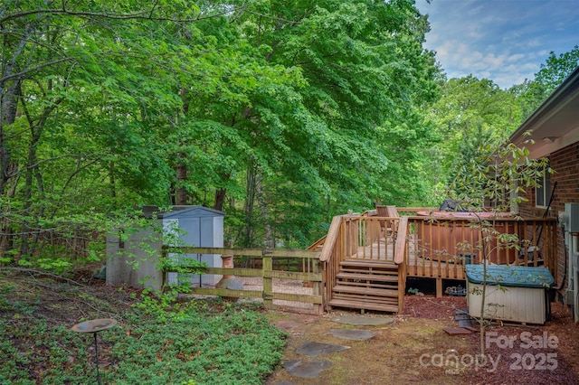 view of yard featuring fence, a storage shed, a wooden deck, a view of trees, and an outdoor structure