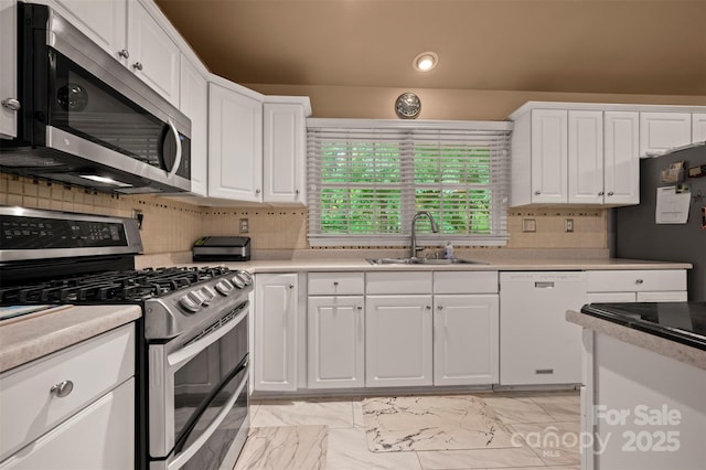 kitchen featuring white cabinets, appliances with stainless steel finishes, a sink, and light countertops