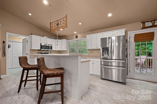 kitchen featuring light countertops, appliances with stainless steel finishes, vaulted ceiling, and white cabinetry