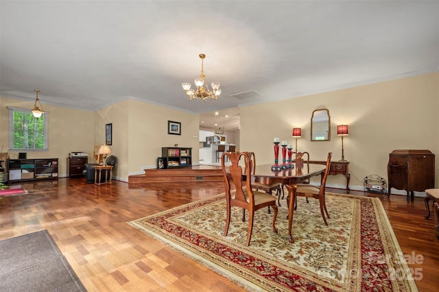 dining space featuring baseboards, ornamental molding, wood finished floors, and a notable chandelier