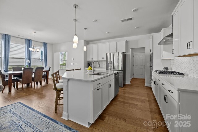 kitchen featuring visible vents, appliances with stainless steel finishes, tasteful backsplash, a sink, and a chandelier