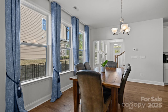 dining space featuring baseboards, visible vents, dark wood-style floors, and a notable chandelier