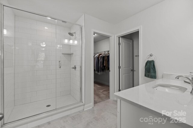 bathroom featuring a spacious closet, a shower stall, and vanity