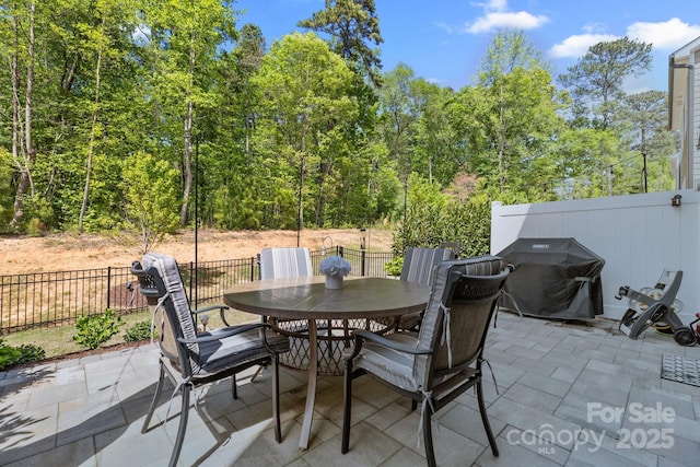 view of patio featuring grilling area, fence, and outdoor dining area