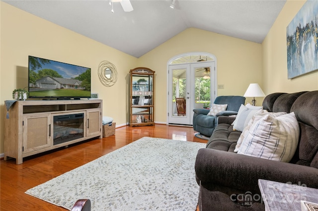 living area featuring baseboards, ceiling fan, vaulted ceiling, and wood finished floors