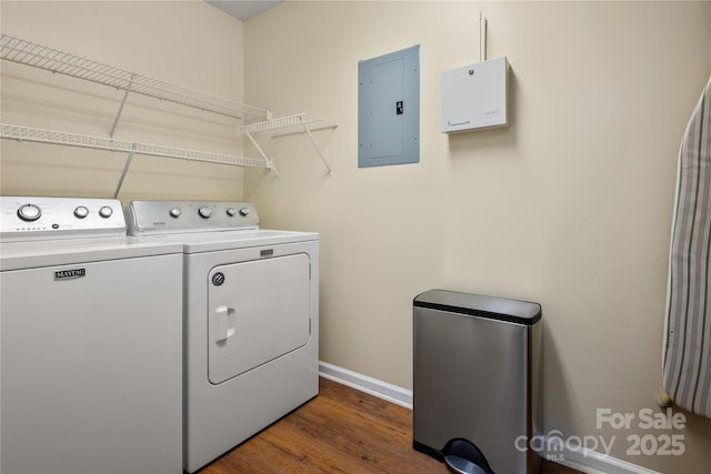 clothes washing area featuring electric panel, laundry area, dark wood-style flooring, baseboards, and washer and dryer