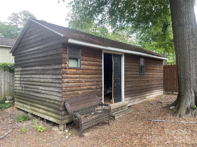 view of outbuilding featuring fence, an outbuilding, and entry steps