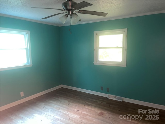 unfurnished room featuring healthy amount of natural light, a textured ceiling, ornamental molding, wood finished floors, and a ceiling fan