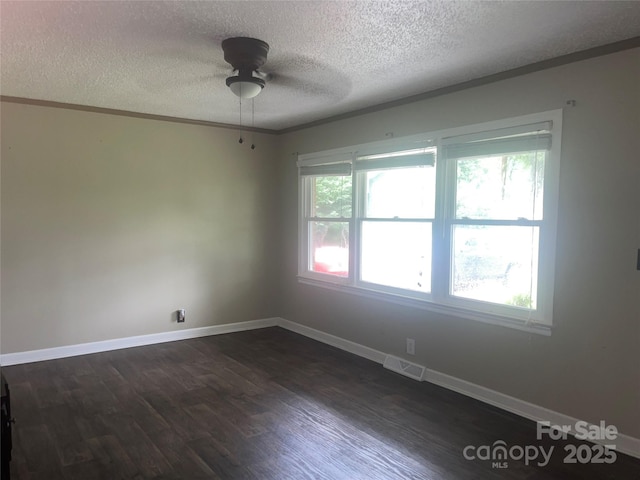 spare room with a textured ceiling, ceiling fan, ornamental molding, dark wood-style flooring, and baseboards